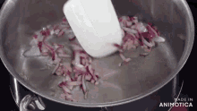 a pan of chopped onions is being stirred with a spatula and the words made in animatica are visible in the corner