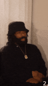 a man with a beard wearing a black hat and a gold necklace