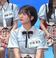 a girl wearing a blue shirt and tie has a name tag that says ' a ' on it