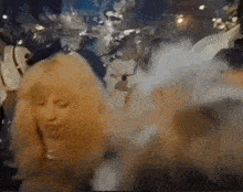 a woman with long blonde hair is dancing in a crowded room .
