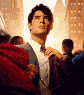 a man in a suit and tie adjusts his tie in front of a crowd of people