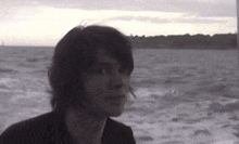 a man with long hair is looking out over the water