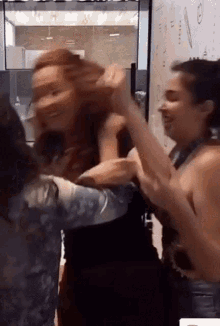 a group of women are fighting in a room with a white board in the background .