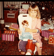 a little girl is sitting on a rocking horse holding a doll