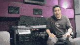 a man in a timberland shirt sits in front of a keyboard and monitors