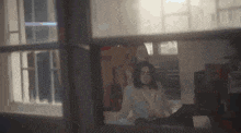 a blurry picture of a woman sitting on a bed in front of a window