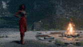 a woman in a red dress is dancing near a fire
