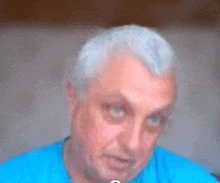 a man with gray hair is wearing a blue shirt .
