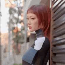 a woman with red hair leaning against a fence