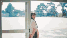 a girl in a school uniform is standing in front of a door .