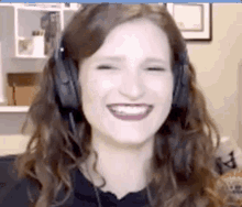 a woman is wearing headphones and smiling while looking at the camera .