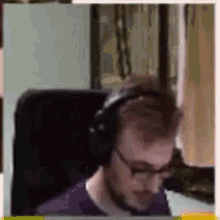 a man wearing headphones and glasses is sitting in front of a computer .