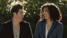 a man and a woman are standing next to each other with the word max on the bottom right