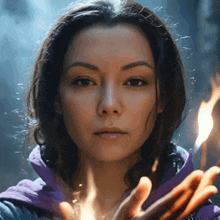 a woman in a purple jacket is holding a torch in her hands