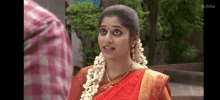 a woman in a red and gold sari is talking to a man .