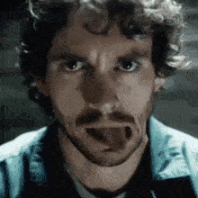a man with a beard is sticking out his tongue .