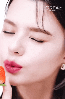 a close up of a woman eating a strawberry with l' oreal paris written in the corner