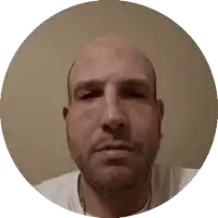 a bald man with a beard looks at the camera