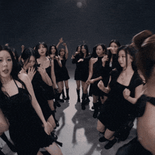 a group of women in black dresses are dancing