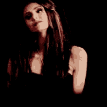 a woman with long hair is wearing a black top and a necklace .