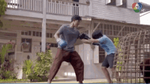 a man and a boy are boxing in front of a house