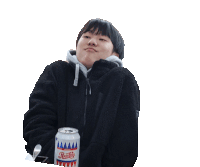 a young man in a black jacket is holding a can of soda and making a funny face