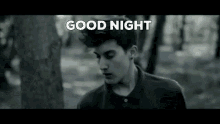 a black and white photo of a young man in the woods with the words `` good night '' above him .