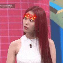 a woman with red hair is wearing a white top and a microphone .