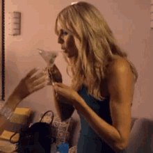a woman is drinking from a martini glass while standing in front of a couch .