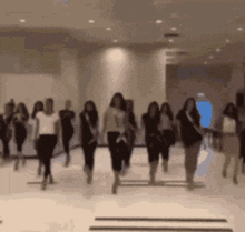 a group of women are dancing in a room with a blue light in the background