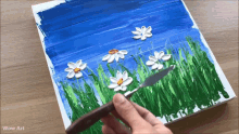 a person is painting flowers in a field with a spatula