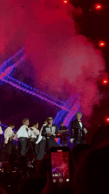 a group of people are standing on a stage with smoke coming out of it