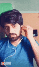 a man with a beard is wearing ear buds and a gif maker app on his phone