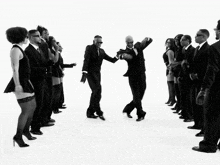 a group of men in suits are dancing in front of a crowd of women