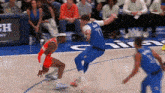 a group of basketball players are playing a game on a court with a crowd watching .