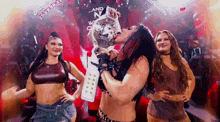 a woman is holding a trophy in front of her face while two other women are standing behind her .