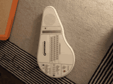 a white omnichord sits on a striped carpet
