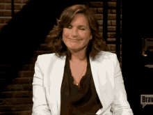 a woman in a white jacket is smiling in front of a sign that says braw