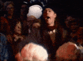 a man in a top hat and scarf is standing in a crowd of people .