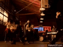 a group of people are dancing in a room with a guitar player