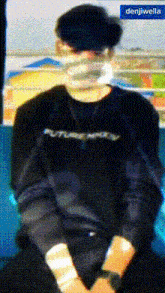 a man wearing a mask and a future ready shirt is sitting on a train