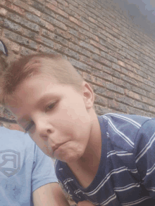 a boy wearing a blue shirt with the letter j on it looks down
