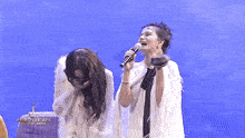 two women singing in front of a sign that says miss entertain