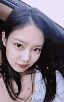a woman with long black hair is wearing a white shirt and a necklace