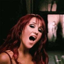 a woman with red hair is making a face with her mouth open .