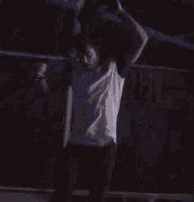 a man in a white shirt is sitting in a boxing ring with his arms in the air .