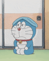 doraemon is sitting on the floor in front of a door .