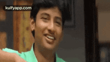 a young man in a green shirt is smiling and laughing .
