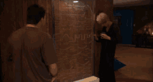 a man and a woman are standing in front of a wall with a maze on it that says ' maze ' on it