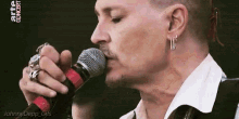 a man is singing into a microphone while wearing earrings .